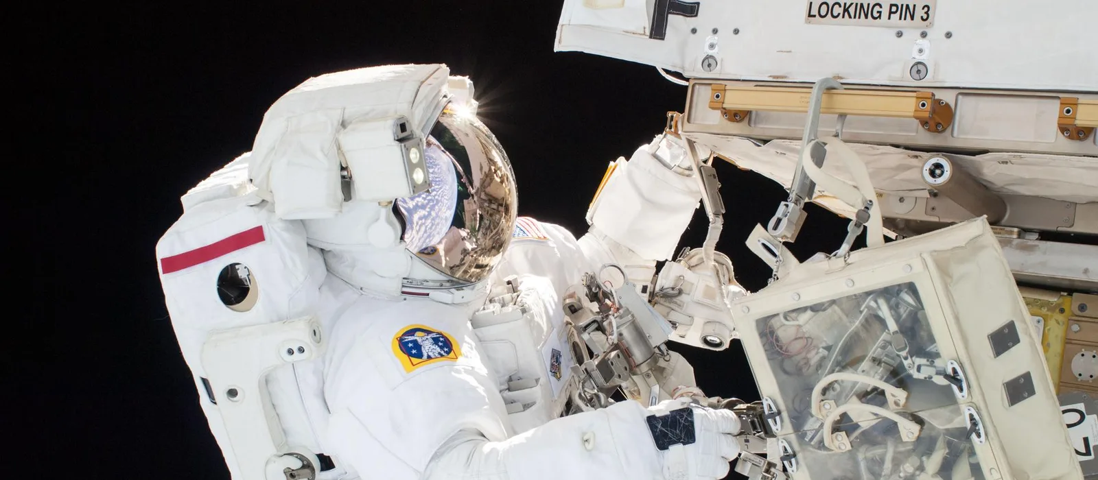 An astronaut on a spacewalk, Earth reflected in the gold visor