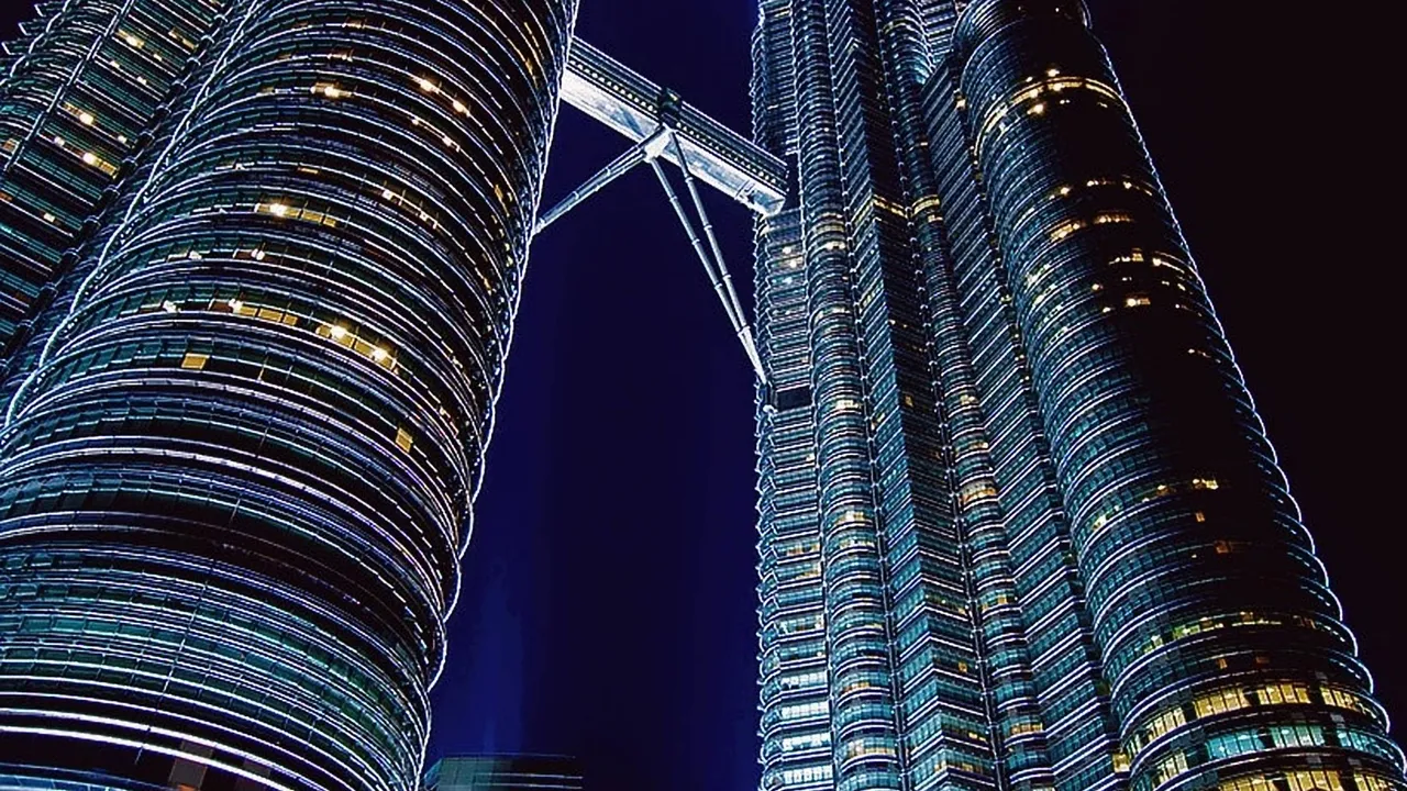 The Petronas Twin Towers and skybridge lit up at night in Kuala Lumpur
